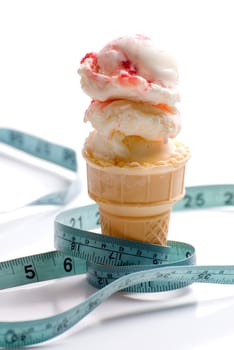 Concept image of a diet featuring an ice cream cone with strawberry ice cream and a measuring tape shot on white