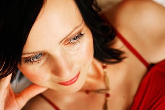 A close-up portrait of a beautiful and elegant Caucasian woman with blue eyes and wearing a red dress.