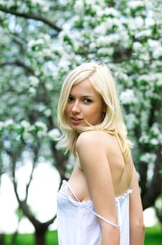 Young beautiful woman in a white dress in blooming gardens