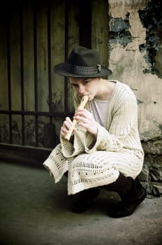 Young girl in a hat playing flute on the street