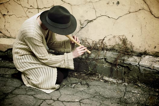 Young girl in a hat playing flute on the street