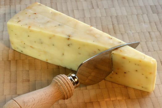 white cheddar cheese with basil and tomato on bamboo cutting board with knife