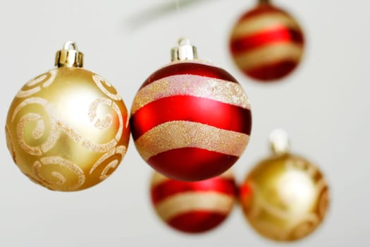 A close-up of red and gold colored decorative Christmas baubles hanging down.