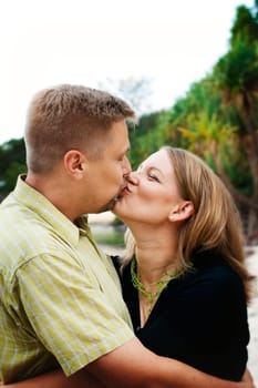 A portrait of a happy married couple kissing while outdoors.
