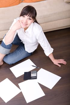 happy young woman with calculator at home