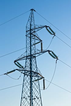 High voltage pylon with cables on blue sky background