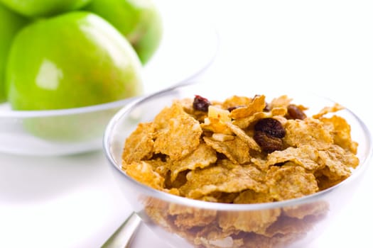 cornflakes and green apples in glass bowls on white background