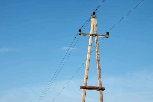 Old wooden electric pillar against blue sky