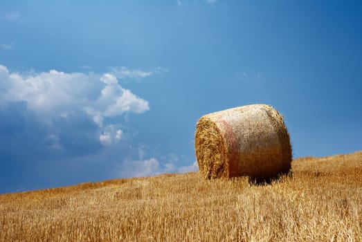 Solitary straw bale under moody sky