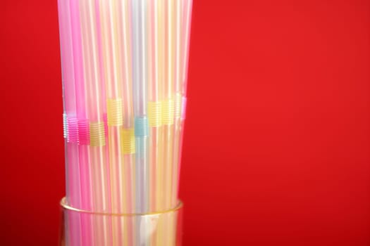 Colorful plastic drink straw over red copy space background