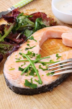 grilled salmon steak on wooden board with salad