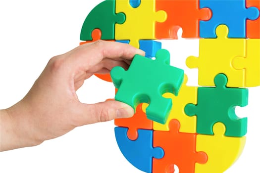 Hand with color slice puzzle trying insert it on place