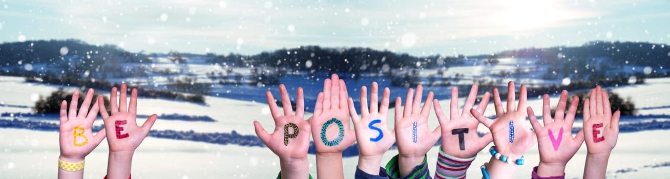 Children Hands Building Colorful English Word Be Positive. White Winter Background With Snowflakes And Snowy Landscape.