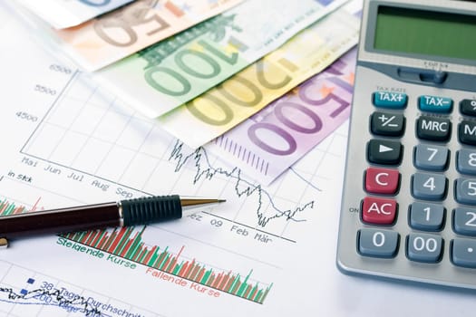 Closeup of a stock chart with Euro banknotes, calculator and pen