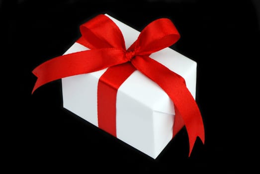 white gift box with red ribbon isolated on black background