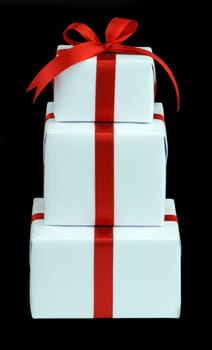 three white gift boxes with red ribbon isolated on black background