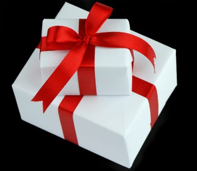 two white gift boxes with red ribbon isolated on black background