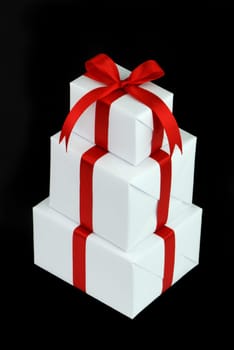 three white gift boxes with red ribbon isolated on black background