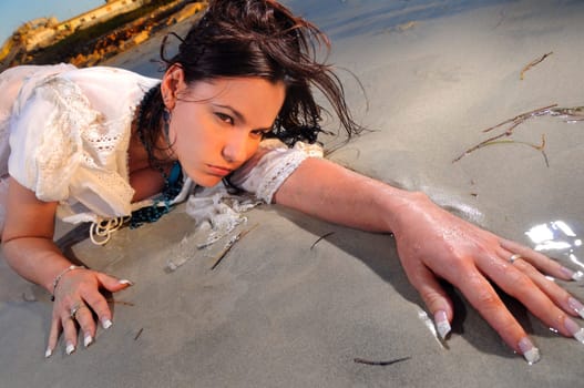 Portrait of young wet woman laying on the sand