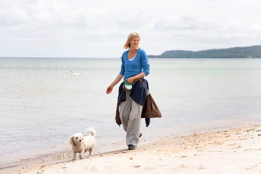 Woman walking the dog on the beach