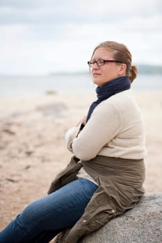Woman sitting on a rock with a thoughtful expression