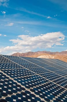 solar panel with blue sky, clouds, and mountains in the background