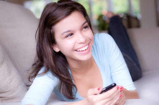 A young attractive woman lying on the sofa at home with phone
