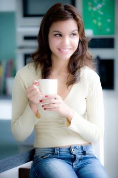 A young woman having coffee in the kitchen