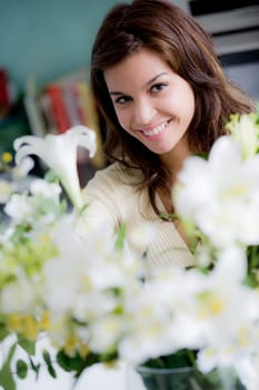 A pretty young woman arranging flowers in the kitchen