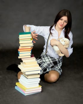 Schoolgirl with the big pile of books and toy dog