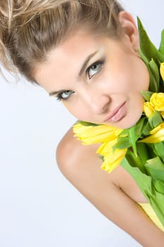 Close-up fresh blonde lady with beautiful make-up with tulips