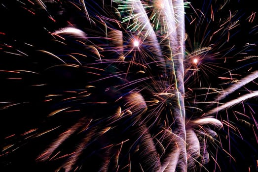 Fireworks exploding in the dark of the evening sky.