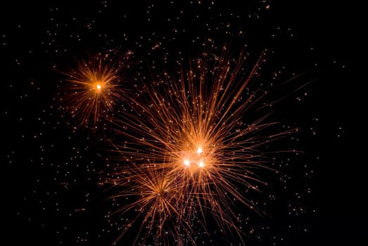 Fireworks exploding in the dark of the evening sky.