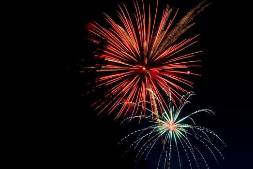 Fireworks exploding in the dark of the evening sky.