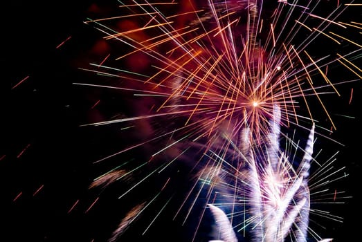Fireworks exploding in the dark of the evening sky.