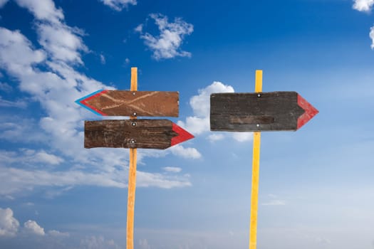 Direction signs against blue sky with white clouds
