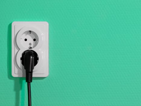 White electric socket on green wall
