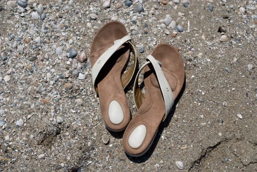 A pair of slippers in the sand by the beach