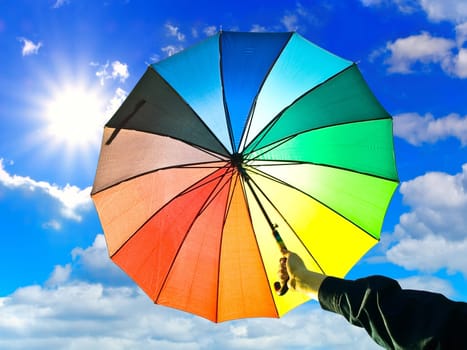 milticolored umbrella in hand against blue sky