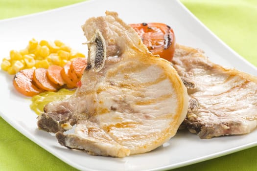 tasty pork chop with corn carrot tomato isolated
