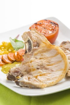 tasty pork chop with corn carrot tomato isolated