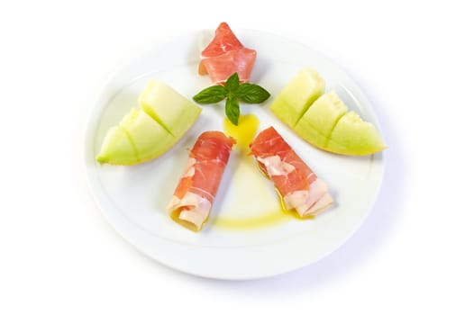 A dish with raw ham, yellow melon and olive oil