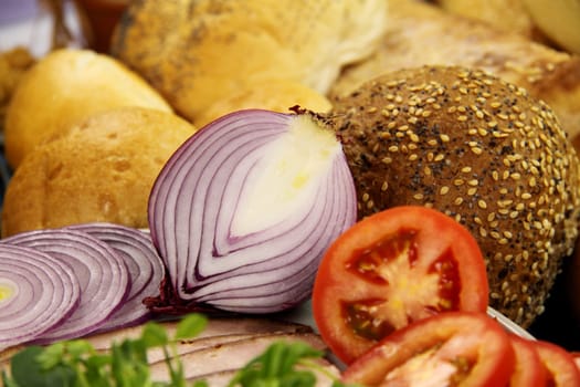 Sliced red onion with tomato and a selection of bread.