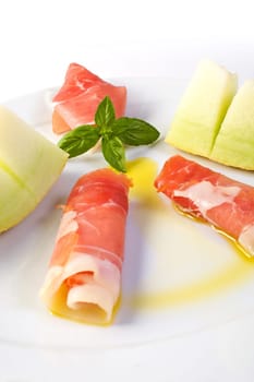 A dish with raw ham, yellow melon and olive oil garnish