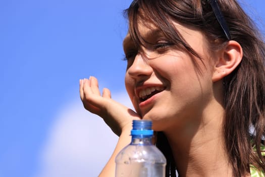 Girl drinking water against blue sky in sunny day