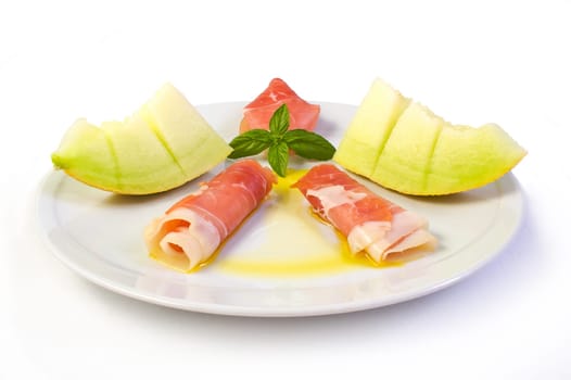 A dish with raw ham, yellow melon and olive oil