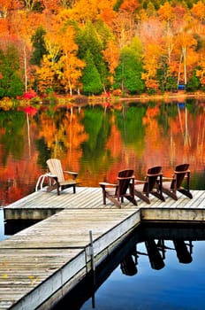 Wooden dock with chairs on calm fall lake