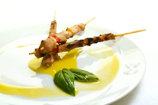 A dish with three little skewers and olive oil garnish