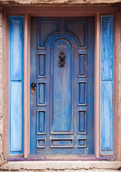 Old peeling blue door with metal knocker