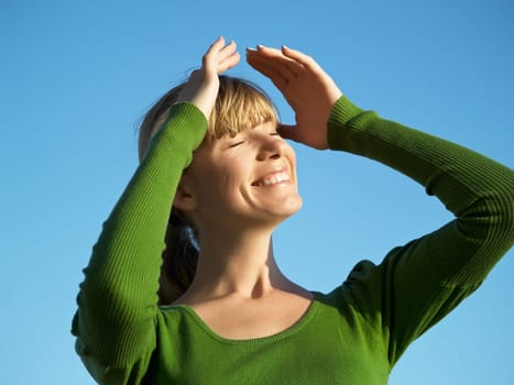 Portrait of the young woman posing on a background of the dark blue sky